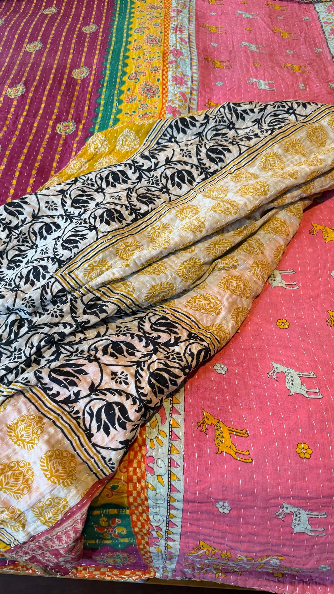 Folded Kantha quilts — black-and-white floral print over pink cloth patterned with deer